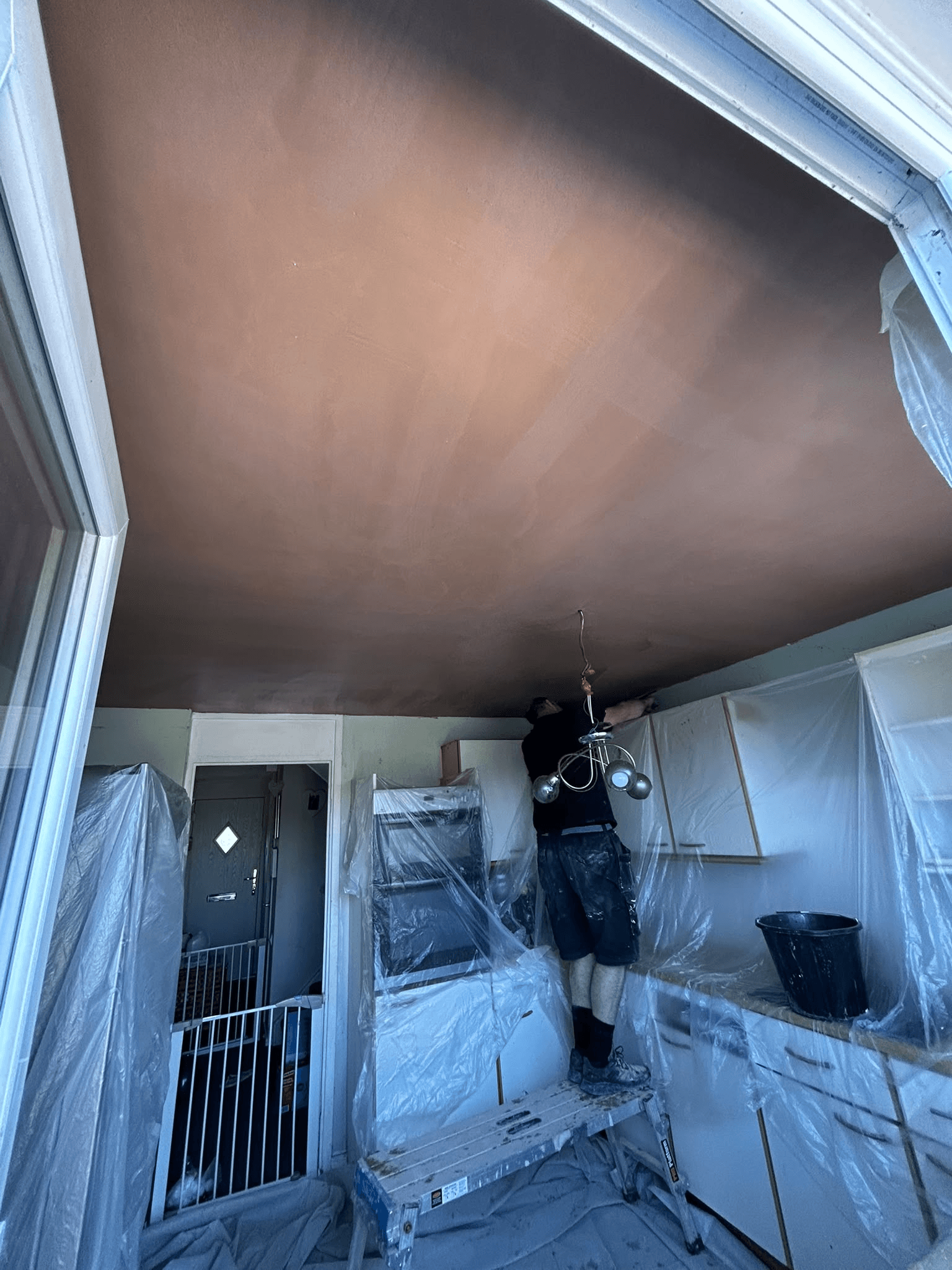 Tradesman plastering a kitchen ceiling