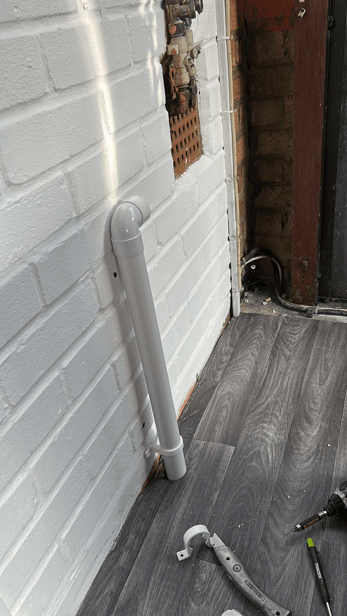 New plumbing pipe installation against brick wall